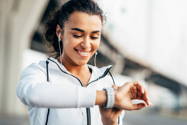 A woman smiles while checking her fitness tracker during a workout, symbolizing wearable fitness tech evolution.