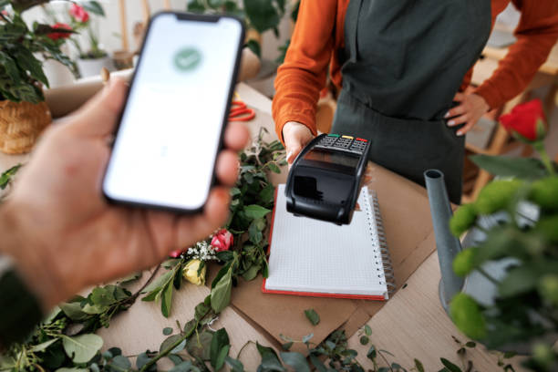 A person makes a payment via NFC using a smartphone in a flower shop.